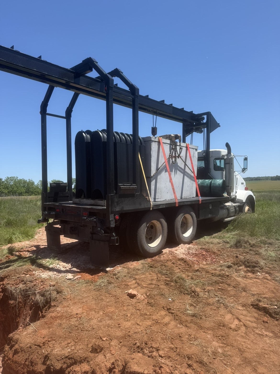 Freedom Septic truck hauling a concrete tank and chambers to a job site